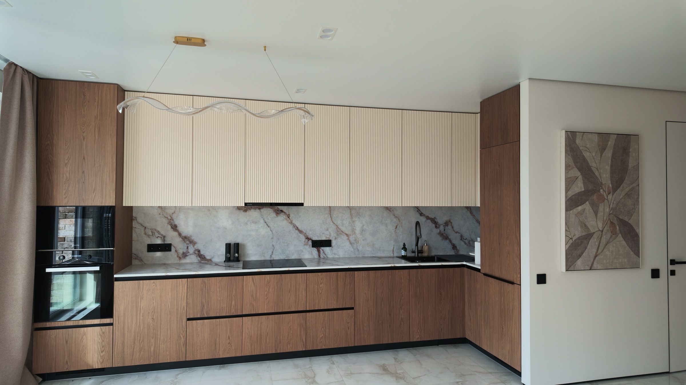 Угловая кухня с кремовыми фасадами до потолка и встроенной техникой Miele